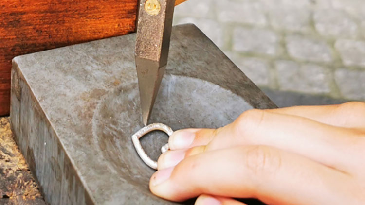 Goldschmiede hämmern ein Herz aus Silber.